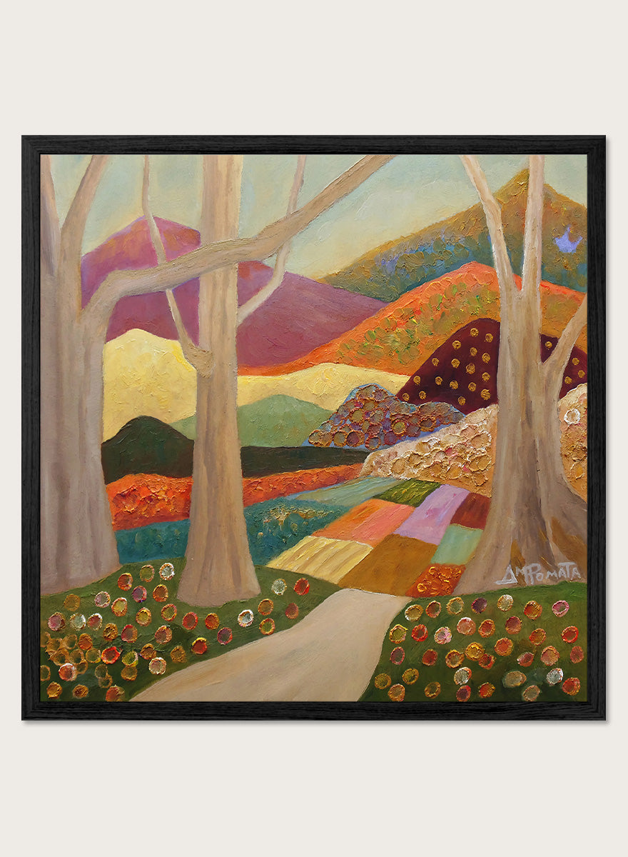 A framed landscape painting featuring stylized trees, a winding path, patchwork fields, and mountains in warm earthy tones. Shop Colorful Field Path by Angeles M. Pomata, an autumn landscape art print featuring a winding path, textured fields, flowers, and rolling countryside.