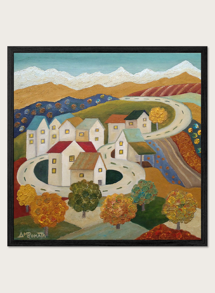A framed folk-art style landscape painting depicting a village with white houses, winding roads, colorful trees, and mountains under a blue sky. Shop Autumn Road Village by Angeles M. Pomata, a colorful autumn landscape art print featuring a winding road, white village houses, fall trees, and distant mountains.
