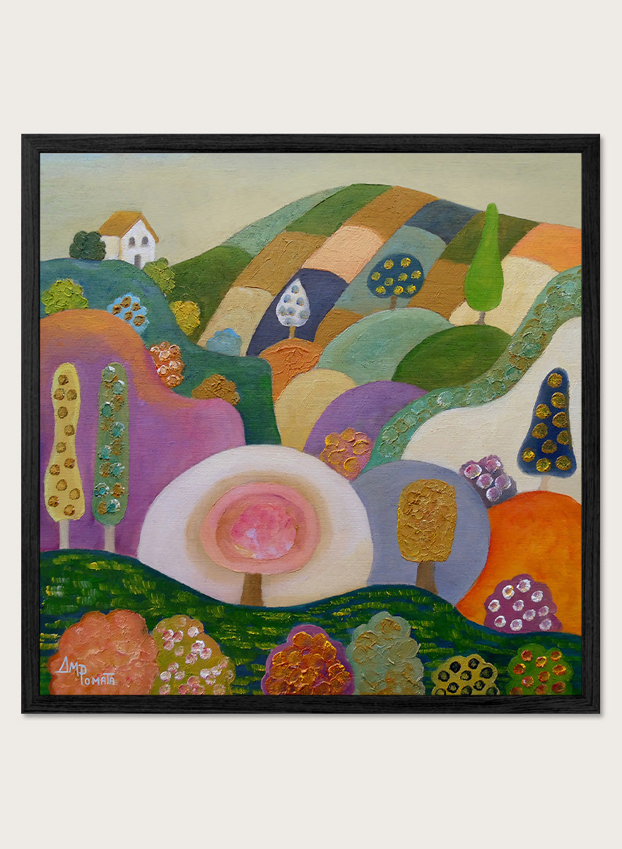 A colorful abstract landscape painting in a black frame, featuring stylized hills, trees, flowers, and a small house. The artwork has a playful, patchwork-like design with multiple vibrant colors including green, purple, orange, pink, blue, and yellow, set against a light beige wall. Shop Whimsical Hillside Village by Ángeles M. Pomata, a colorful landscape art print with rolling hills, patterned trees, and a dreamy village feel.