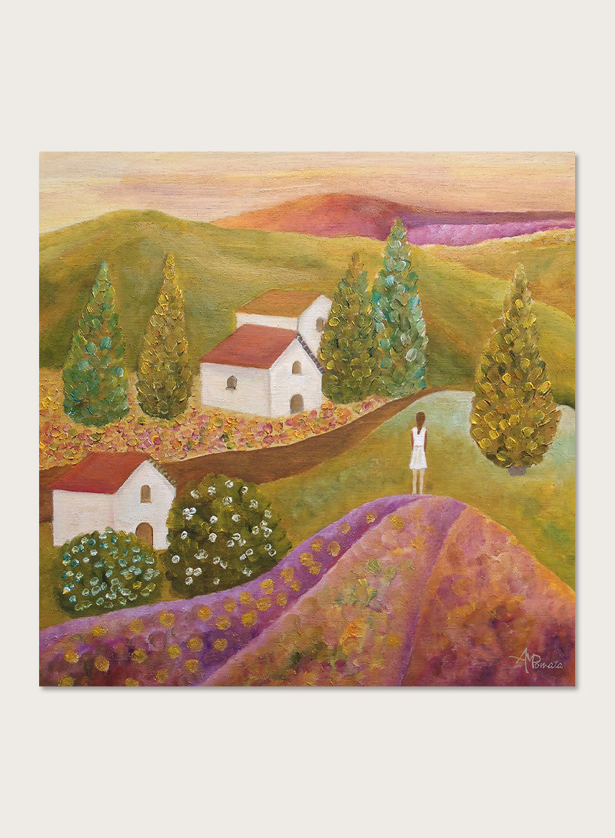 A framed landscape painting featuring rolling green hills, white houses with red roofs, tall conical trees, and a figure standing on a purple field. Shop Woman in Lavender Fields by Angeles M. Pomata, a colorful landscape and figurative art print featuring lavender fields, white houses, cypress trees, and rolling hills.