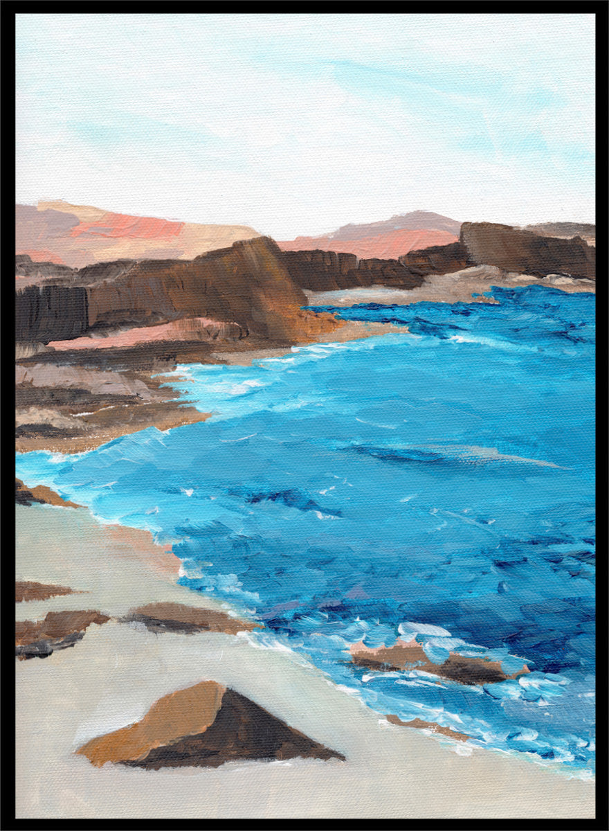 A framed landscape painting depicting a coastal scene with bright blue ocean water, sandy shore, dark rocky cliffs, and distant hills under a pale sky. Shop Rocky Coastal Waters by Nikita Jariwala, a coastal wall art print poster with blue ocean water, rocky cliffs, and a peaceful seaside view.