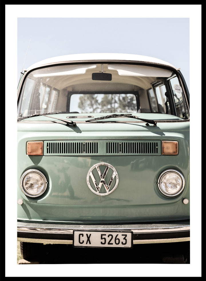 Front view of a vintage green Volkswagen van with clear sky background. Classic Design In Soft Green Tones by Shot by Clint car art print featuring a vintage Volkswagen camper van in soft sage green and warm sunlight.