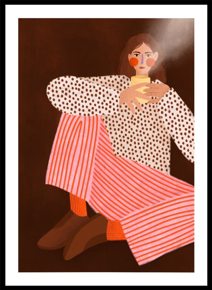 A framed art print featuring a stylized illustration of a woman in a white blouse with brown polka dots and pink-and-white striped trousers, holding a yellow cup against a dark brown background. Cozy Coffee Moment by Bea Müller premium framed fine art print featuring a woman curled up with a warm mug in bold pink, red, and brown tones.