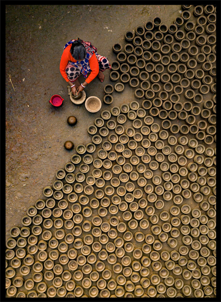 Person working with clay pots on a textured surface. Pot Making by Azim Khan Ronnie aerial photography print showing clay pots drying in Bangladesh village, traditional craft wall art poster