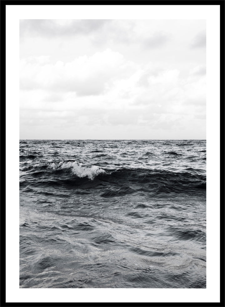 Black and white photographic art print of ocean waves under a cloudy sky. Endless Waves by Shot by Clint black-and-white ocean photography print featuring rolling water, textured surf, cloudy skies, and dramatic coastal movement.