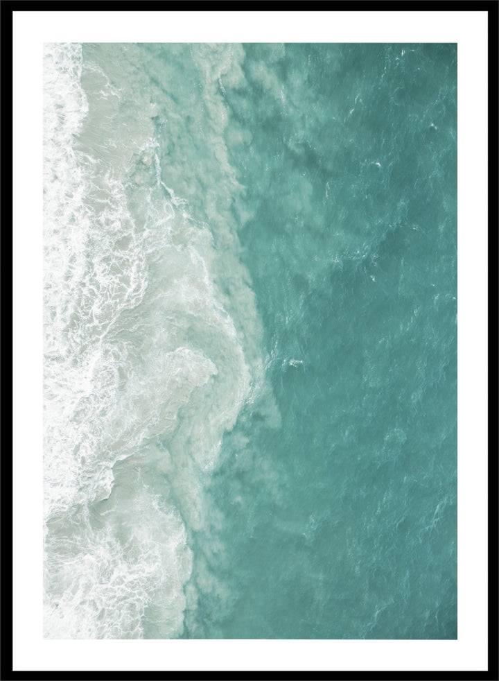 A framed aerial photograph of ocean waves, showing white foam breaking into turquoise and teal water. Ocean’s Edge by Shot by Clint aerial ocean photography print featuring turquoise water, white surf, and layered coastal movement.