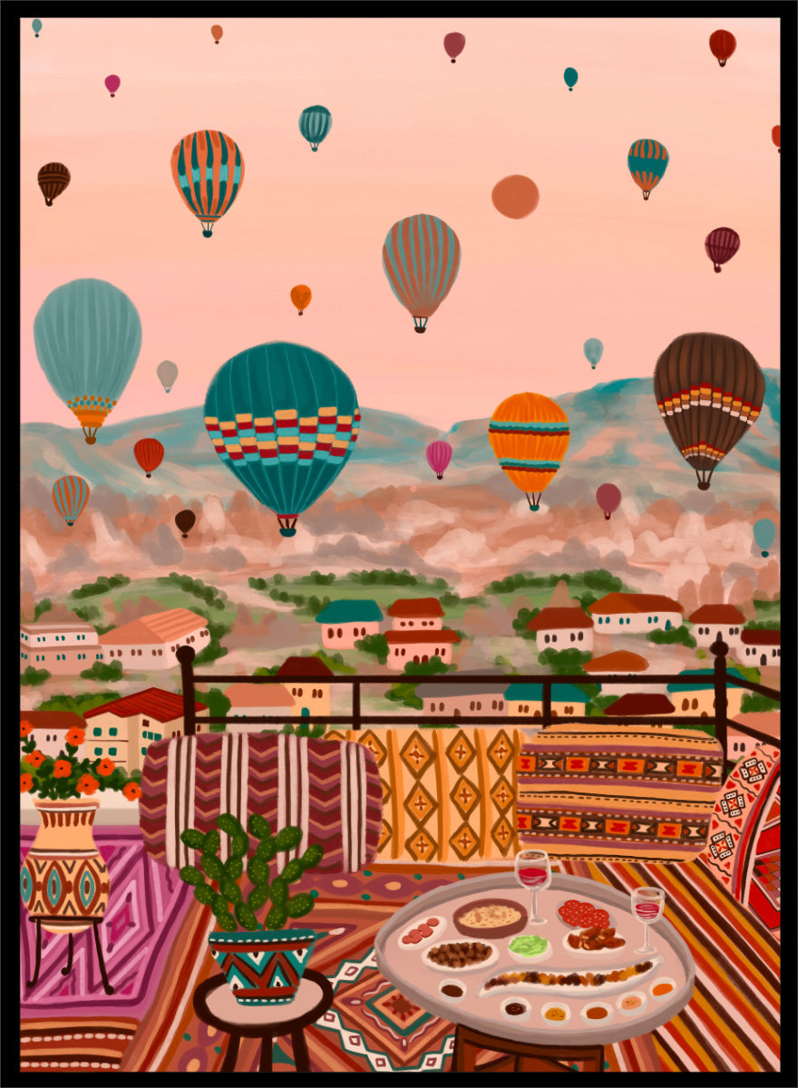 A colorful art print depicting a scenic view of a hillside town with mountains in the background, filled with hot air balloons. In the foreground, a patterned outdoor seating area features a table with food and a potted plant. Shop Balloons Over Rooftop Dinner by Nidhi Kachhadiya, a colorful travel wall art print featuring hot air balloons, rooftop dining, patterned textiles, and teal and coral tones.