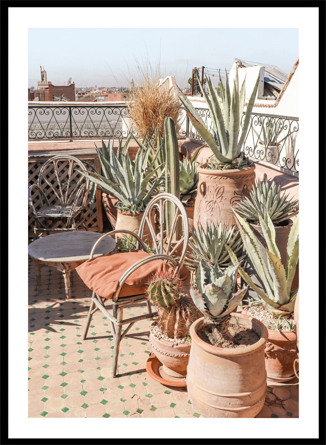 Potted plants on a balcony with a cityscape in the background. Moroccan Cactus Patio by Henrike Schenk captures a Moroccan rooftop terrace with cacti, terracotta pots, and desert-inspired photography wall art.