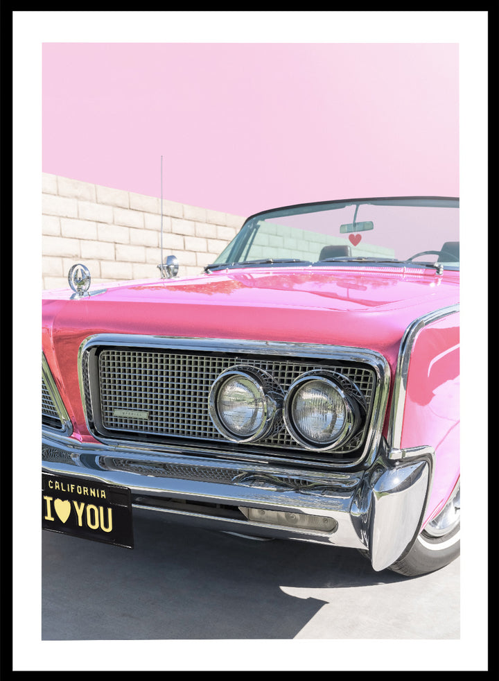 Pink vintage car with 'I ❤️ YOU' license plate against a pink sky. P.S. I Love You by Tom Windeknecht is officially licensed photography featuring a vibrant pop-art style photo of a car with romantic typography. Framed or unframed.