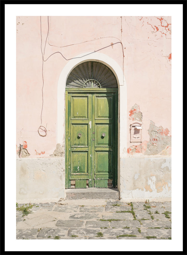 Green door on a pink wall with peeling paint. Old World Green Door by Henrike Schenk features a vintage European doorway, weathered architecture, pastel walls, travel photography, and wall art.