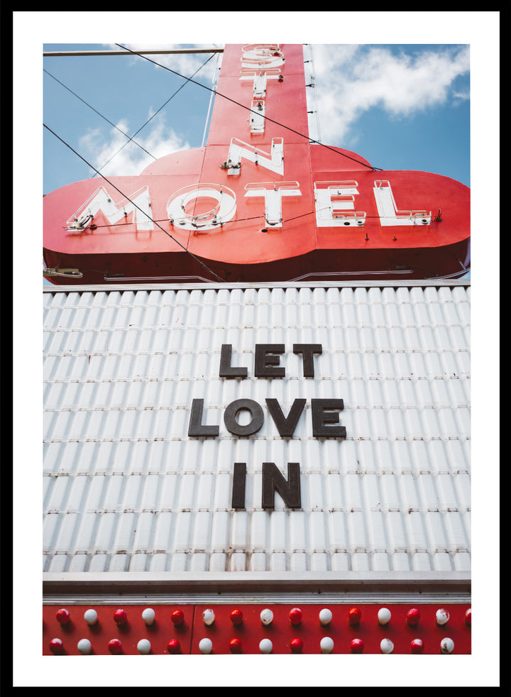 Vintage motel sign with 'Let Love In' message against a blue sky. Let Love In by Bethany Young features a vintage motel sign with red neon lettering against blue sky. Retro Americana photography wall art print.