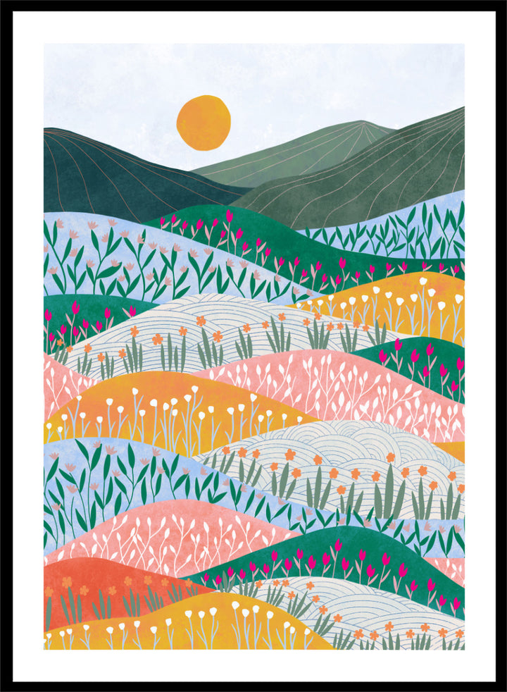 A framed art print featuring a stylized landscape illustration with rolling hills, wildflowers, mountains, and a sun in pastel and bright colors. Colorful Flower Hills by Ceyda Alasar botanical landscape art print featuring layered wildflower fields, rolling hills, mountains, and a golden sun.
