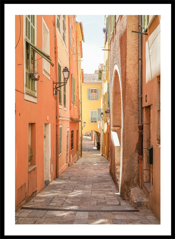  narrow street with colorful buildings in a European city. Vibrant European Alley by Henrike Schenk is a travel photography print featuring a Mediterranean street, cobblestone alley, and pastel European architecture.