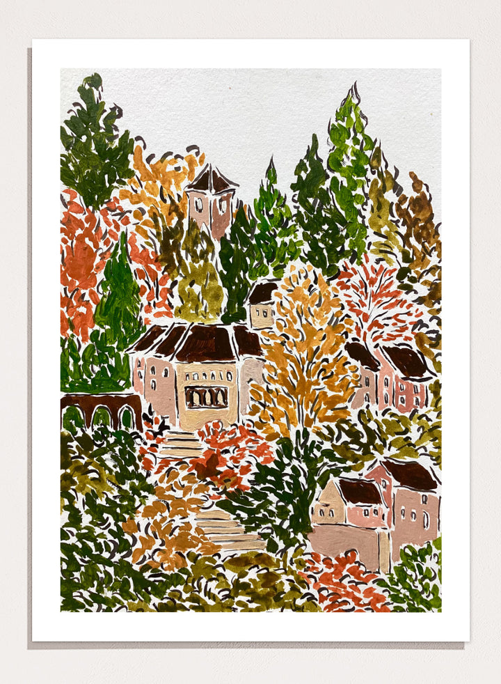 A framed art print featuring a hand-drawn, stylized landscape of a hillside village with beige buildings, brown roofs, and dense trees in green, yellow, orange, and red tones. Shop Autumn Hillside Village by Rushati Chowdhury, a colorful autumn landscape art print with hillside homes, winding steps, dense trees, and warm fall tones.
