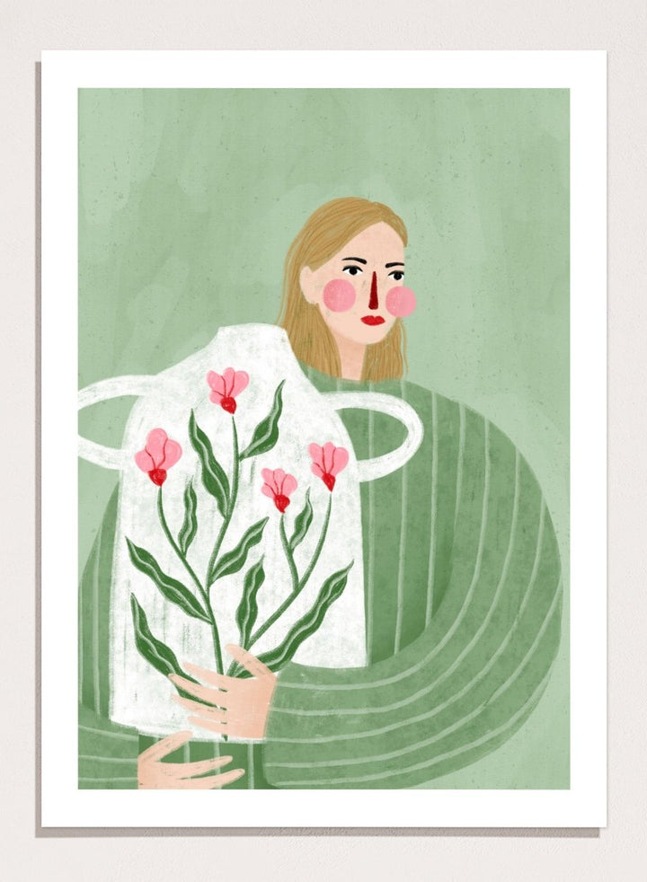A framed art print featuring a stylized illustration of a woman with blonde hair holding a white apron decorated with pink flowers and green leaves, set against a sage green background. Woman Holding Flowers by Bea Müller premium framed fine art print featuring a woman carrying a white vase filled with pink flowers and green leaves.