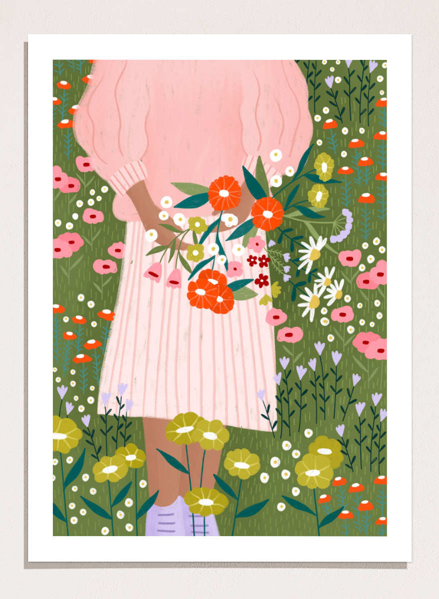 A framed art print featuring a stylized illustration of a person in a pink striped dress holding a bouquet of orange, red, and white flowers in a green field of wildflowers. Secret Garden Bouquet by Bea Müller floral art print featuring a woman gathering wildflowers in a colorful garden filled with poppies, daisies, and greenery.