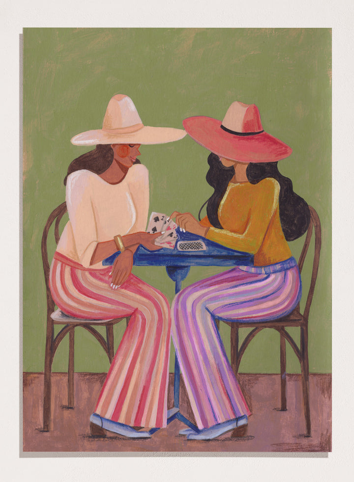 Two women playing cards at a table with colorful clothing and hats against a green background. Stylish Women Play Cards by Caroline Bonne Müller is a fine art print and wall poster featuring two fashionable women playing cards at a table.