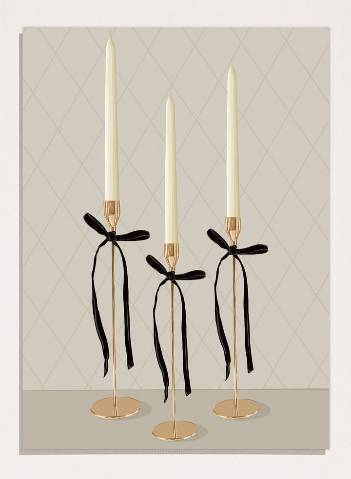 Three gold taper candle holders with cream candles and black ribbon bows, arranged on a light gray surface against a beige diamond-patterned background. Elegant Gold Taper Candles by Lisa Solomoniuk premium framed fine art print featuring gold candlesticks, cream tapers, and long black ribbons.