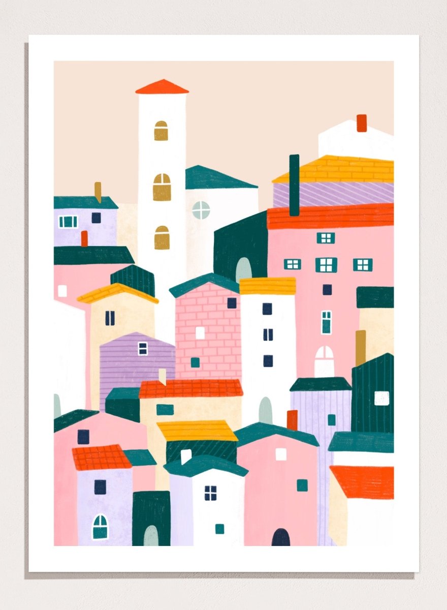 A framed minimalist art print depicting a cluster of stylized pastel houses and a church tower in pink, peach, teal, yellow, and cream tones. Charming Colorful Houses by Bea Müller premium framed fine art print featuring a playful town of pink, lavender, cream, and teal buildings.