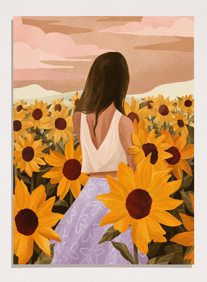 Woman in a white top and purple pants sitting among sunflowers with a scenic background. Sunflower Evenings by Goed Blauw is a fine art print and wall poster featuring a woman standing in a sunflower field with warm golden tones.