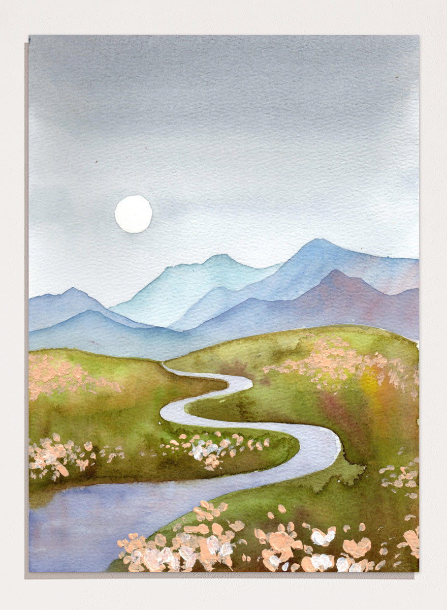 Watercolor landscape painting of a winding river flowing through green hills with pink flowers, blue mountains in the background, and a white sun in a gray sky. Shop Serene Mountain Path by Ekaterina Prisich, a landscape art print featuring a winding valley path, blue mountains, soft flowers, and a white moon.