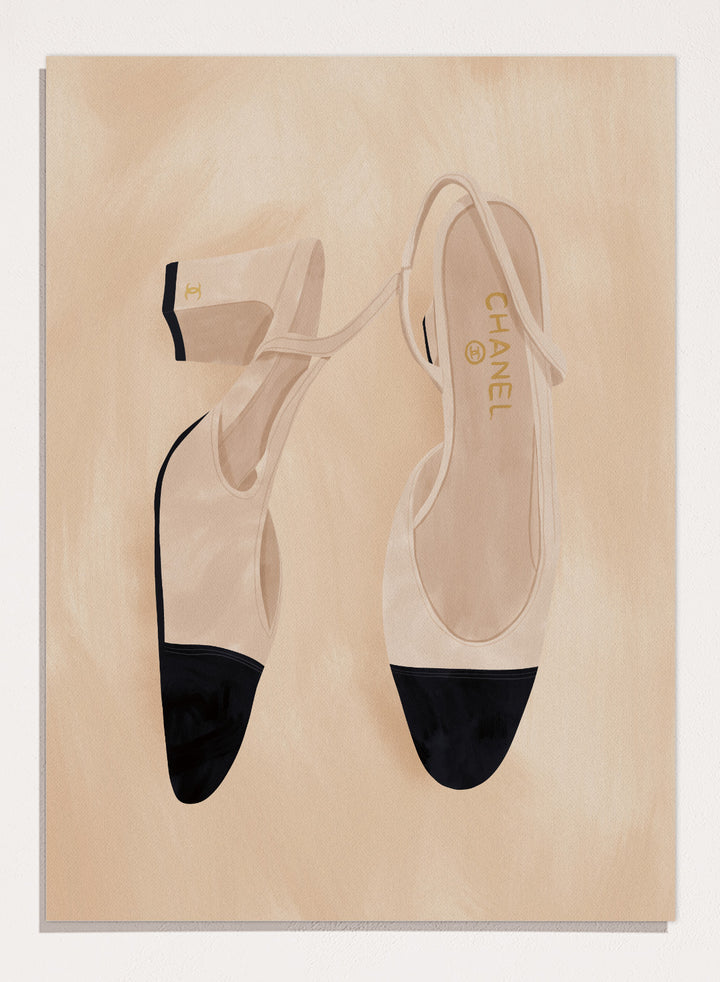 A pair of slingback flats with a beige and black color-blocked design, displayed on a textured beige background with a black border. Chic Cap-Toe Heels by Lisa Solomoniuk premium framed fine art print featuring cream slingback heels with black cap toes on a soft beige background.