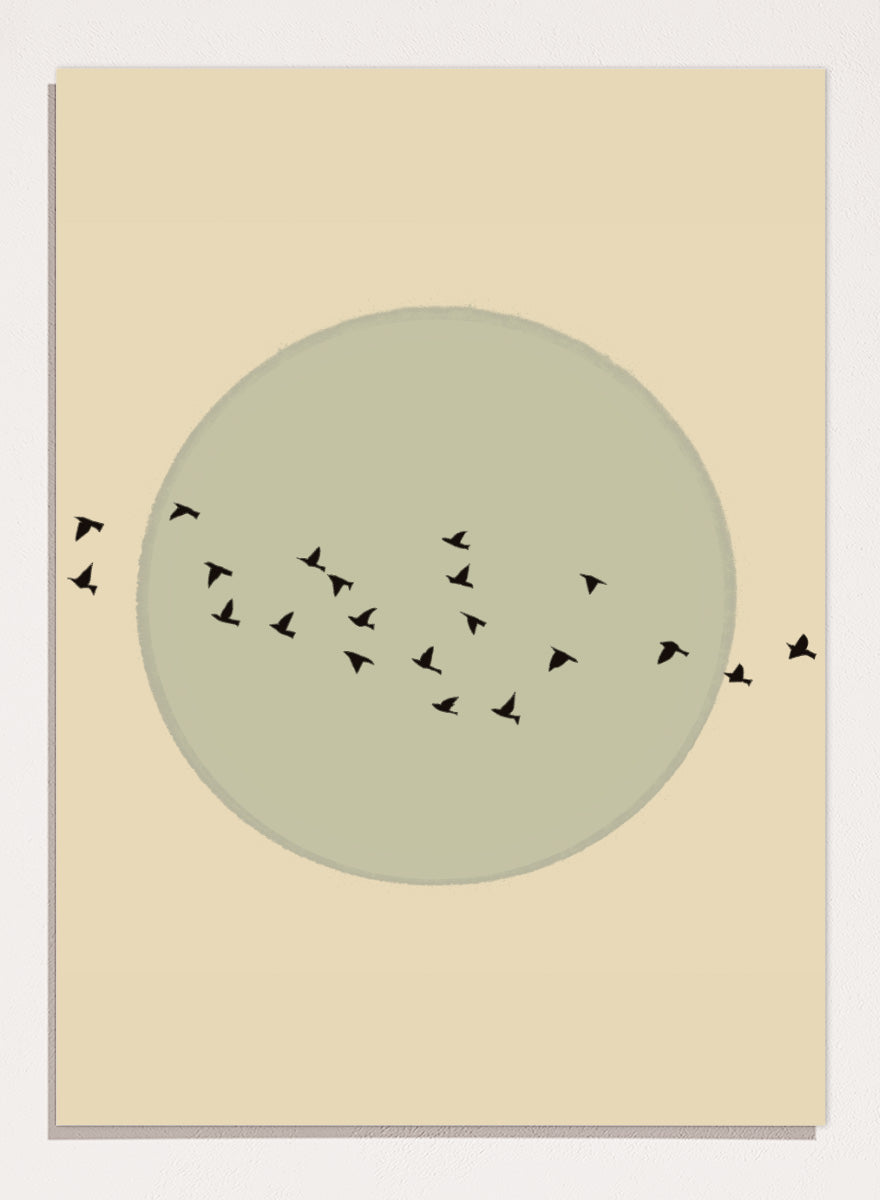 Minimalist art print featuring a large muted sage green circle centered on a warm beige background, with small black bird silhouettes flying around it. Flock Against The Moon by The Art Concept is a minimalist bird art print featuring black birds in flight across a pale green moon and warm cream background.