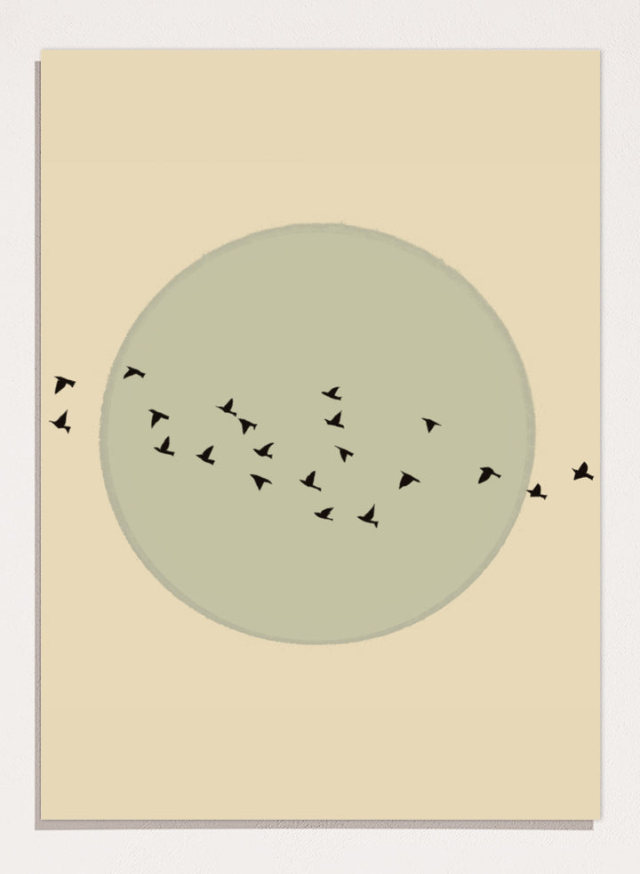 Minimalist art print featuring a large muted sage green circle centered on a warm beige background, with small black bird silhouettes flying around it. Flock Against The Moon by The Art Concept is a minimalist bird art print featuring black birds in flight across a pale green moon and warm cream background.