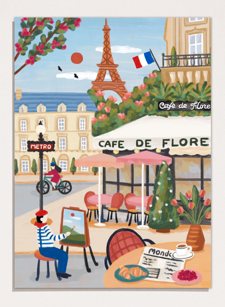 A colorful illustrated Paris street scene with the Eiffel Tower, a cafe exterior labeled Cafe de Flore, a cyclist, a seated painter, flowers, and a French flag. Shop Paris Cafe Life by Nidhi Kachhadiya, a colorful Paris wall art print inspired by French café culture, the Eiffel Tower, and charming European city life.
