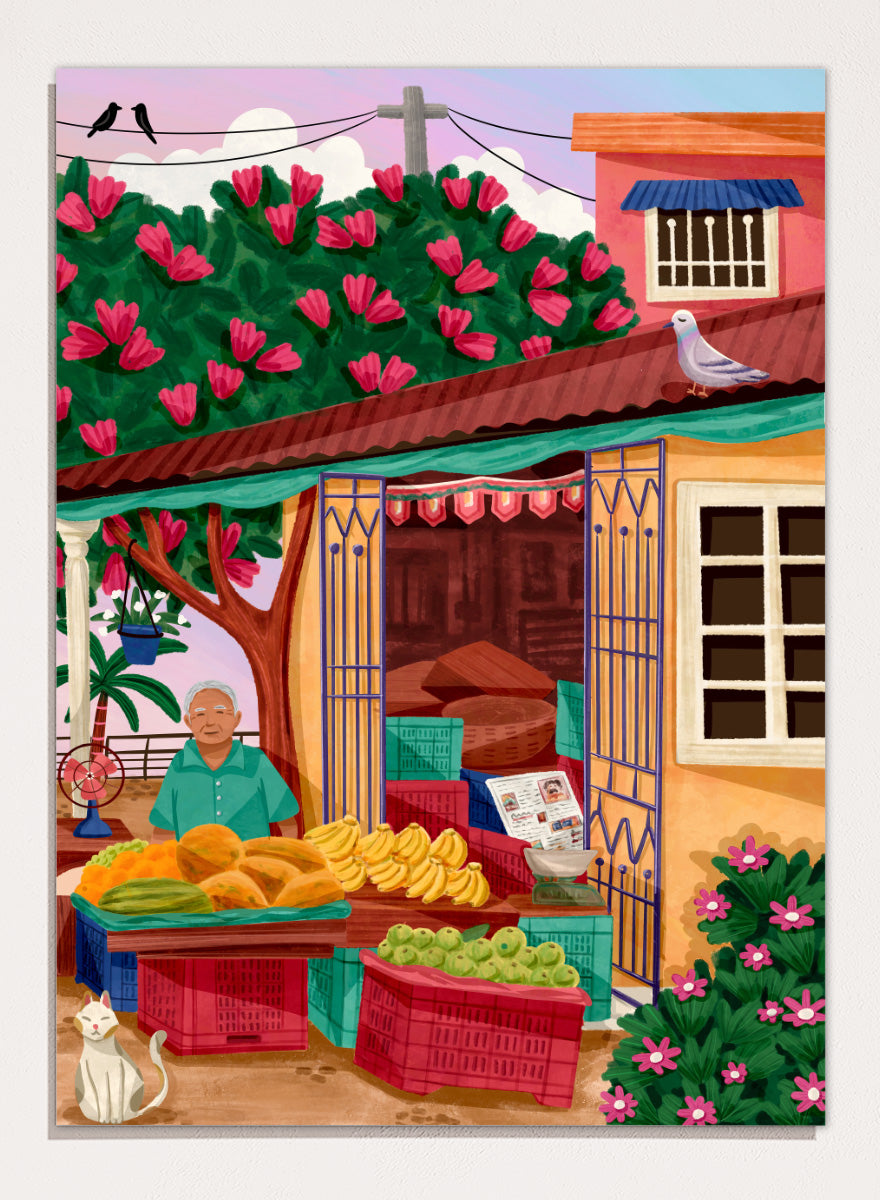A colorful illustrated street market scene with a vendor standing behind tables of fruit and vegetables, a flowering tree, a house with pink flowers, crates, a pigeon on the roof, birds in the sky, and a white cat in the lower left. Colorful fruit stand art print by Nidhi Kachhadiya with fresh produce, floral details, and market charm. A cheerful print for kitchen or dining spaces.