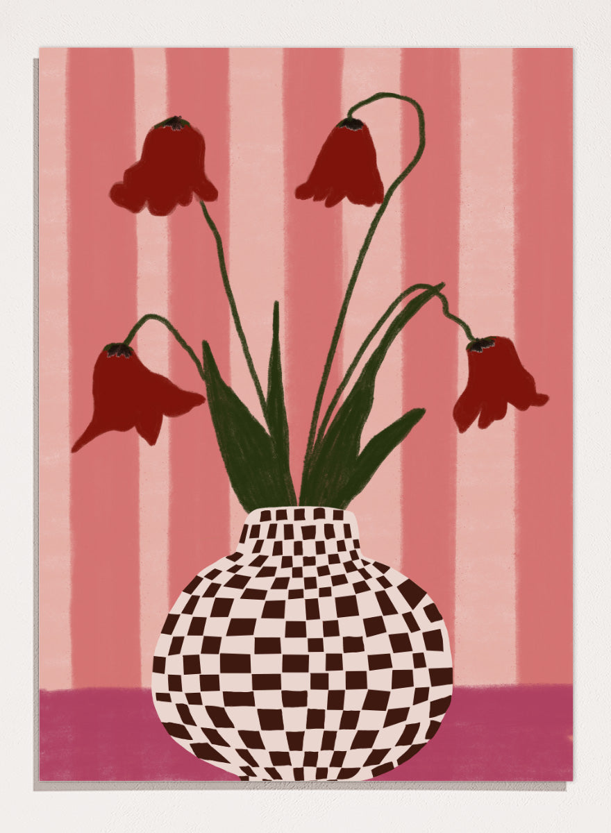 A stylized floral artwork showing four dark red bell-shaped flowers with long green stems rising from a black-and-white checkerboard vase, set against pink vertical stripes and a pink base. Whimsical Flowers Checkered Vase by The Art Concept still life art print featuring red flowers, a checkered vase, and a soft pink striped background.