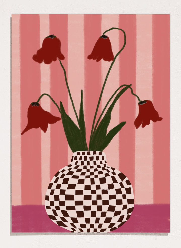 A stylized floral artwork showing four dark red bell-shaped flowers with long green stems rising from a black-and-white checkerboard vase, set against pink vertical stripes and a pink base. Whimsical Flowers Checkered Vase by The Art Concept still life art print featuring red flowers, a checkered vase, and a soft pink striped background.