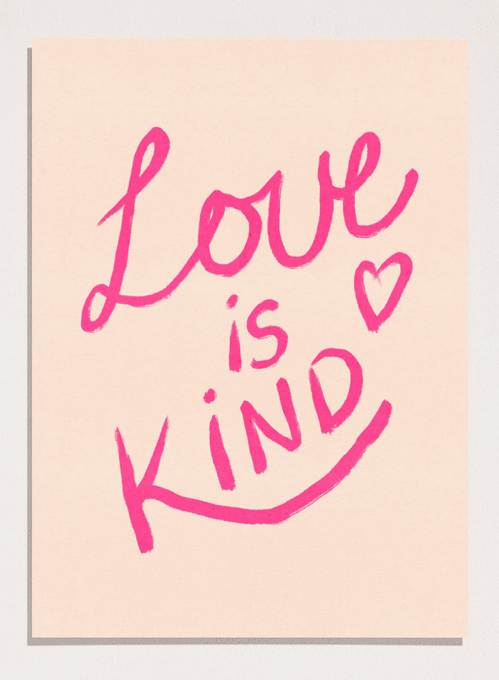 Pink text 'Love is Kind' with a heart on a light pink background. Love Is Kind by Dirkie Nell is a pink typography art print with handwritten lettering and heart detail. A joyful modern love wall poster.