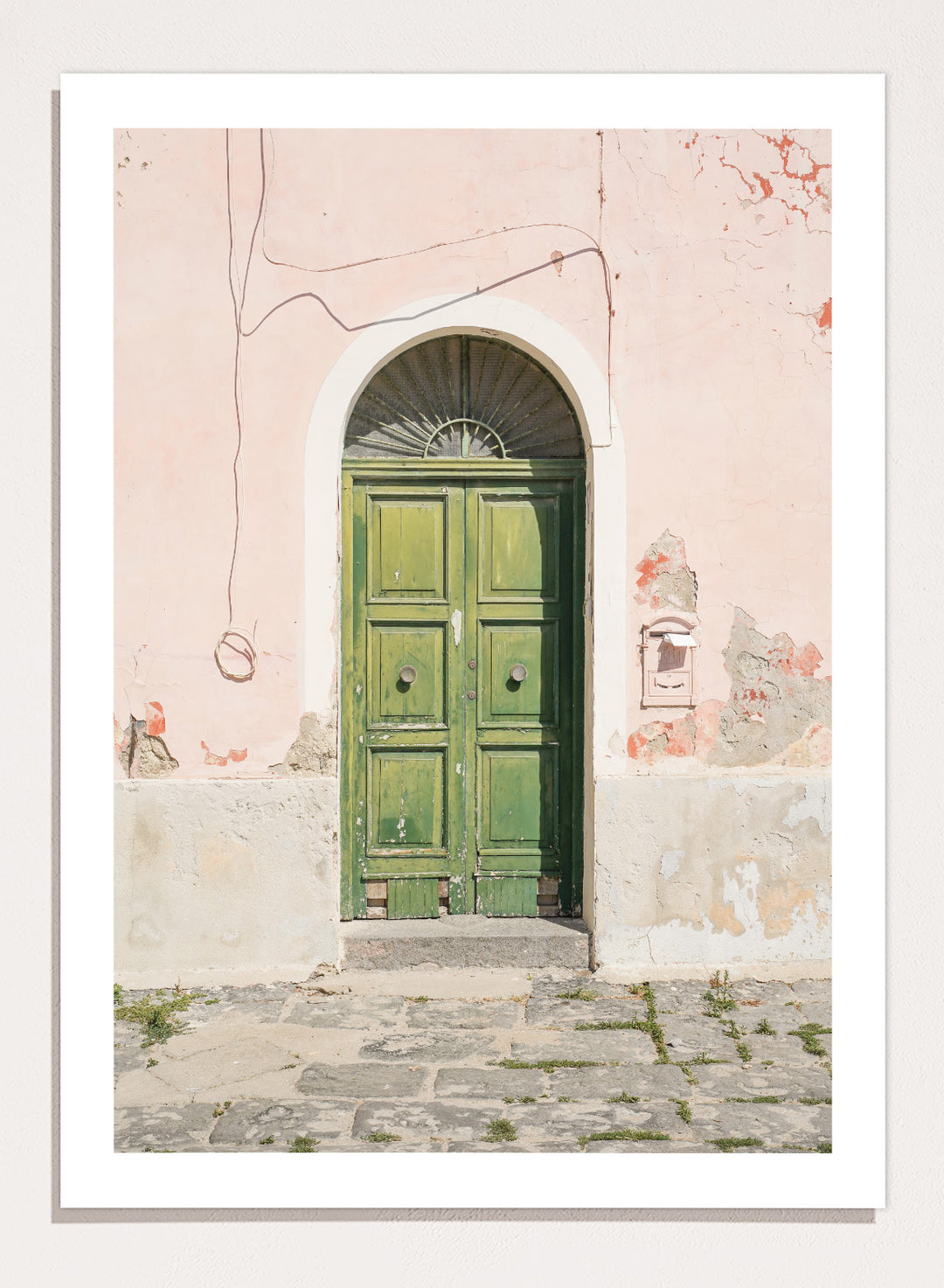 Green door on a pink wall with peeling paint. Old World Green Door by Henrike Schenk features a vintage European doorway, weathered architecture, pastel walls, travel photography, and wall art.