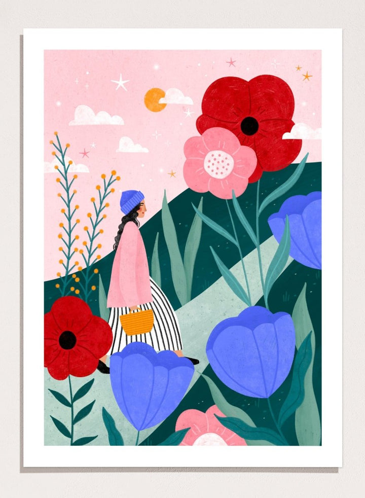 A framed art print featuring a whimsical, colorful illustration of a woman walking through a field of oversized flowers under a pink sky with moon. Whimsical Flower Path by Bea Müller premium fine art print featuring a woman walking among oversized flowers in a bright, playful landscape.