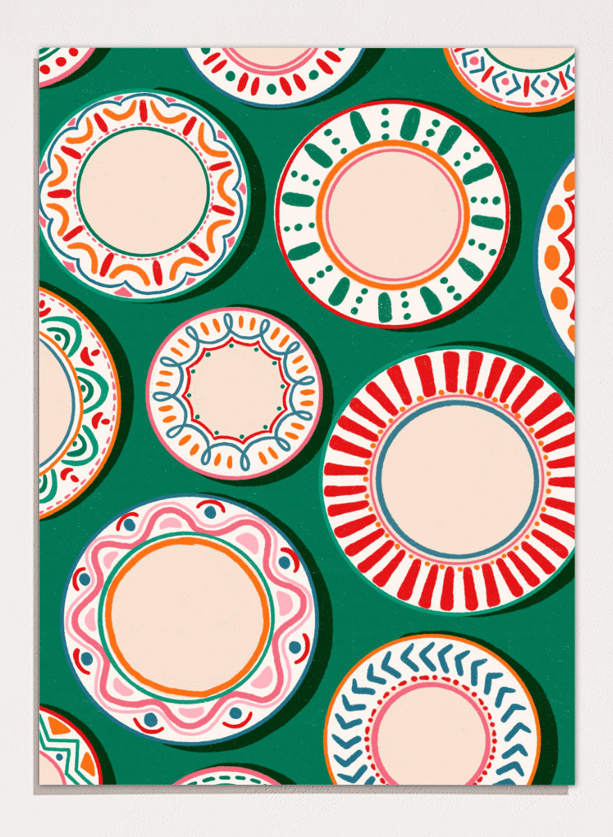 A flat-lay pattern of colorful decorative plates on a dark green background, featuring a variety of circular designs in red, orange, pink, blue, and cream. Shop Colorful Patterned Plates by Nidhi Kachhadiya, a playful kitchen wall art print featuring decorative plates, folk-inspired patterns, and bold green, red, and pink tones.