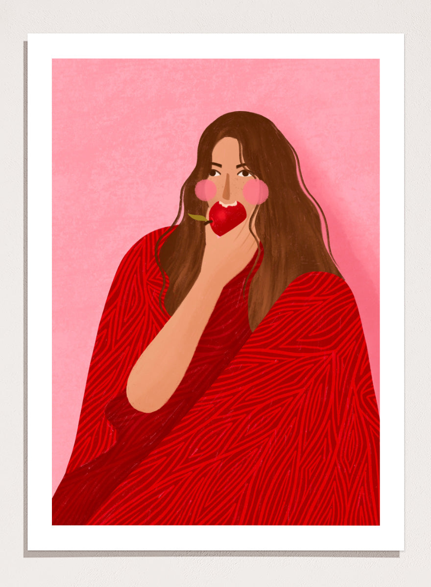 A framed art print featuring a stylized illustration of a woman with long brown hair, wearing a red patterned wrap, holding a red apple to her lips, set against a pink background. Cozy Woman Apple by Bea Müller portrait art print featuring a woman eating a red apple in bold red and pink tones for colorful modern wall decor.