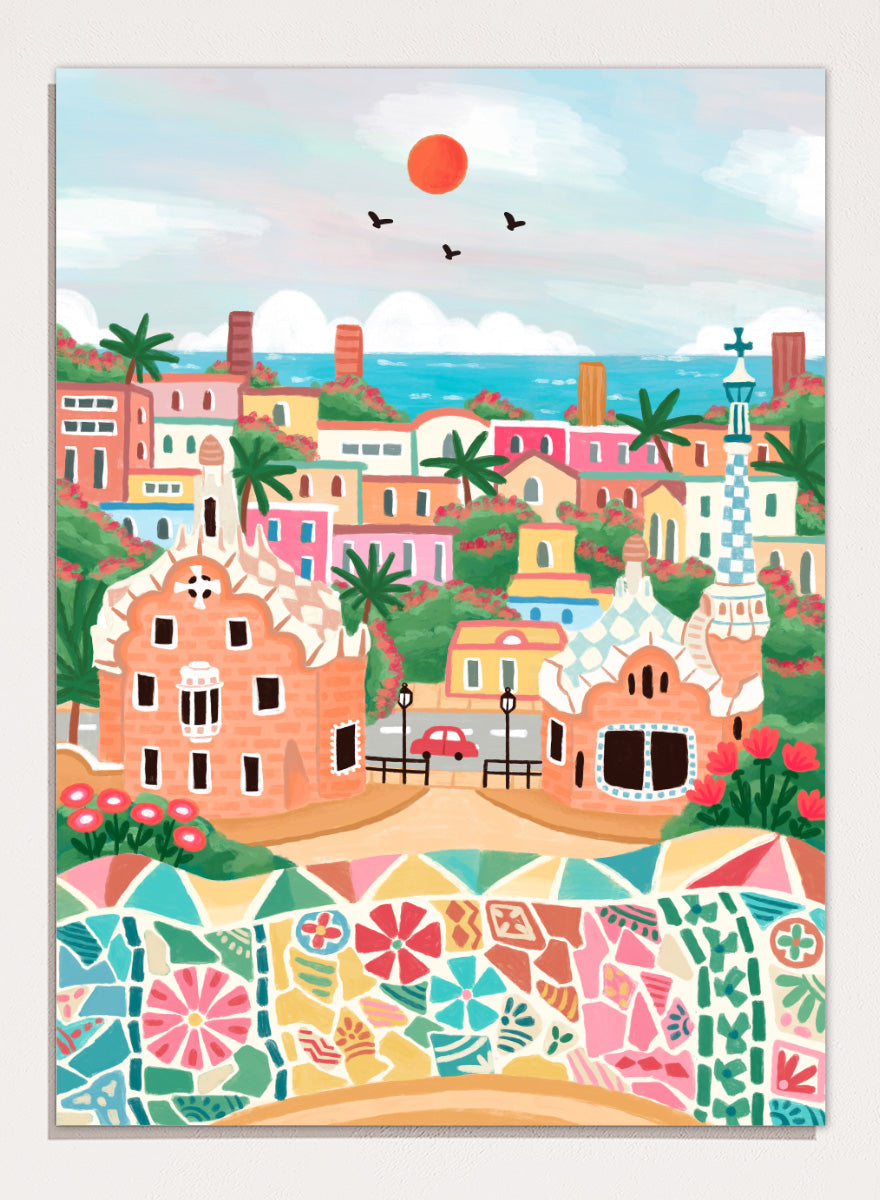 A colorful stylized illustration of a coastal town with pastel buildings, palm trees, a mosaic wall in the foreground, blue sea, and a red sun in the sky. Shop Colorful Coastal Dream by Nidhi Kachhadiya, a vibrant Barcelona wall art print inspired by Park Güell, Gaudí architecture, mosaics, and bright coastal color.