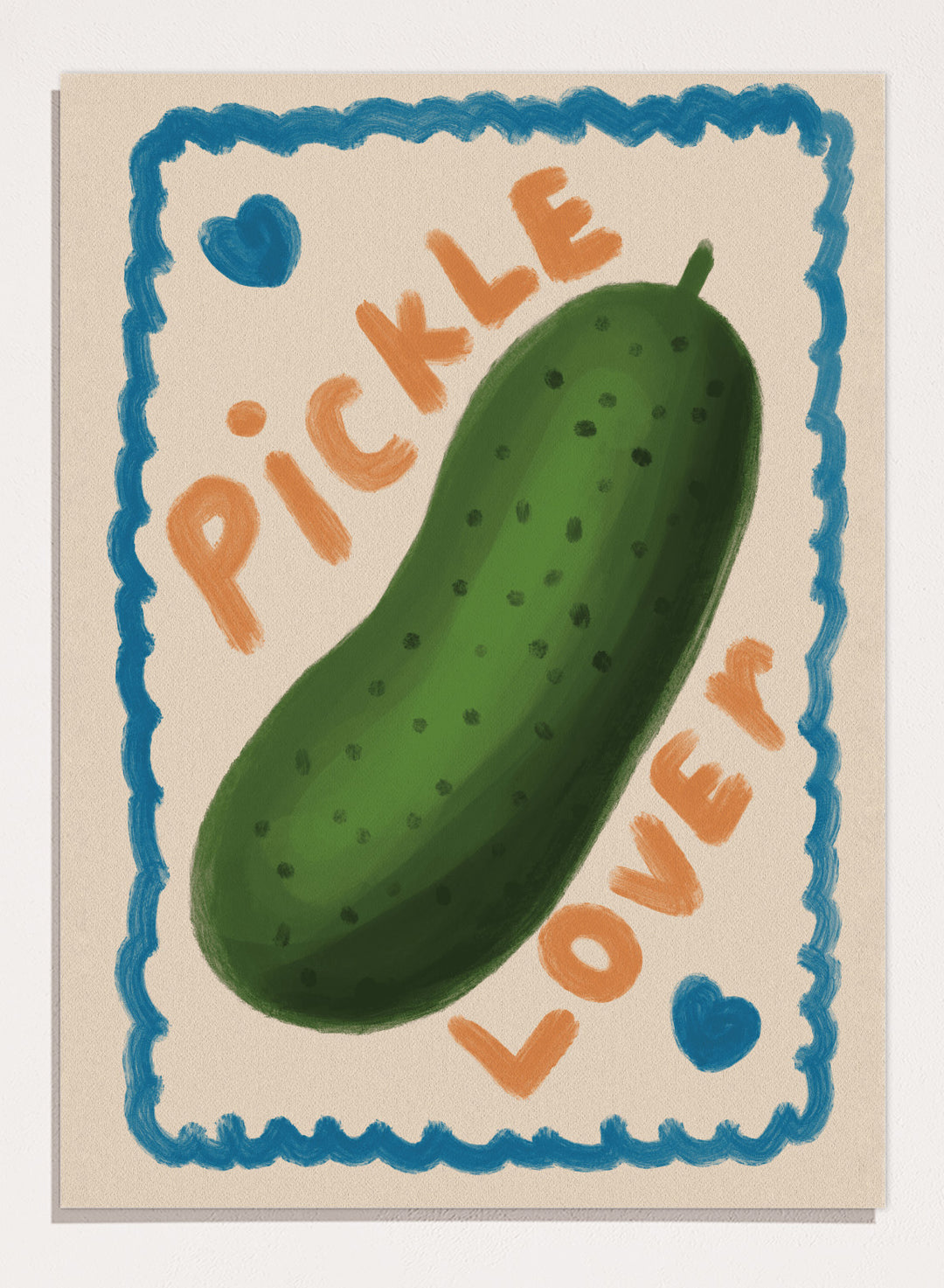 An art print featuring a hand-drawn green pickle centered on a cream background, surrounded by a blue scalloped border. The words &