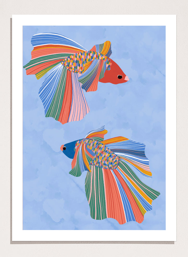 A framed art print featuring two stylized betta fish with vibrant, multicolored striped fins and bodies on a light blue water-like background. Colorful Betta Duo by Ceyda Alasar fish art print featuring two patterned betta fish with flowing fins in bright coral, blue, green, pink, and yellow.