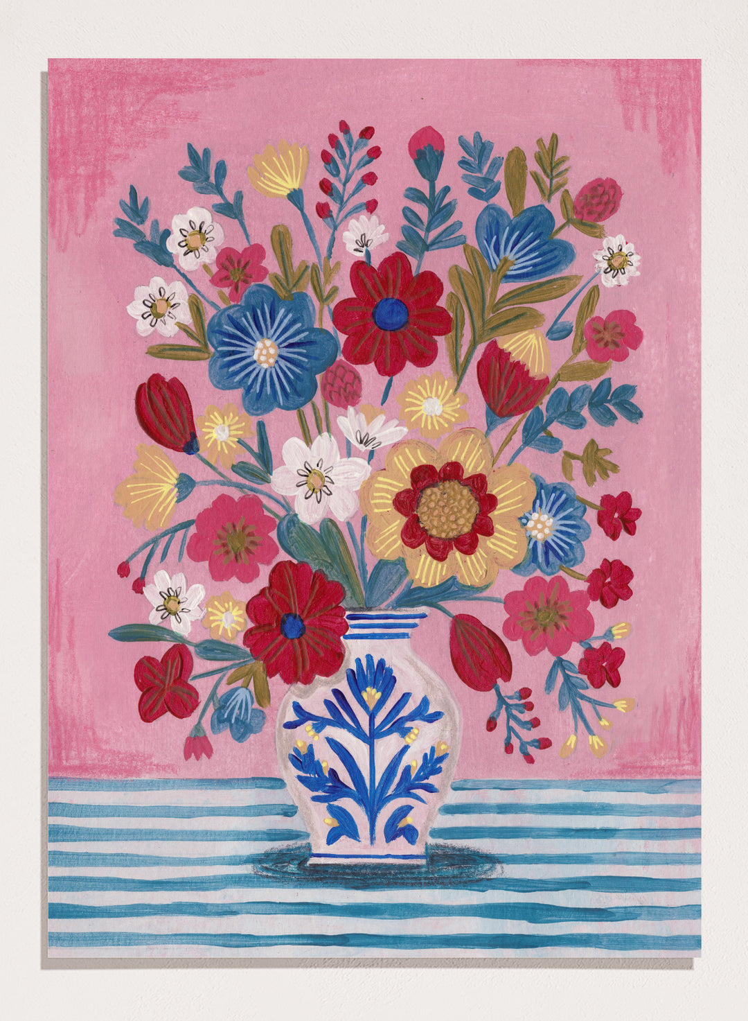 Colorful floral arrangement in a blue and white vase on a pink and blue striped background. Colorful Folk Art Bouquet by Caroline Bonne Müller is a fine art print and wall poster featuring a bright floral arrangement in a patterned vase.
