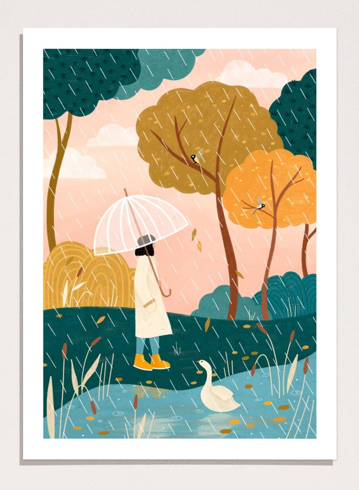 A framed art print featuring a whimsical illustration of a person holding a clear umbrella in the rain near a pond with a white goose, surrounded by stylized trees in teal, mustard, and orange tones. Walking In Autumn Rain by Bea Müller premium framed fine art print featuring a woman with an umbrella beside a pond in a colorful rainy landscape.