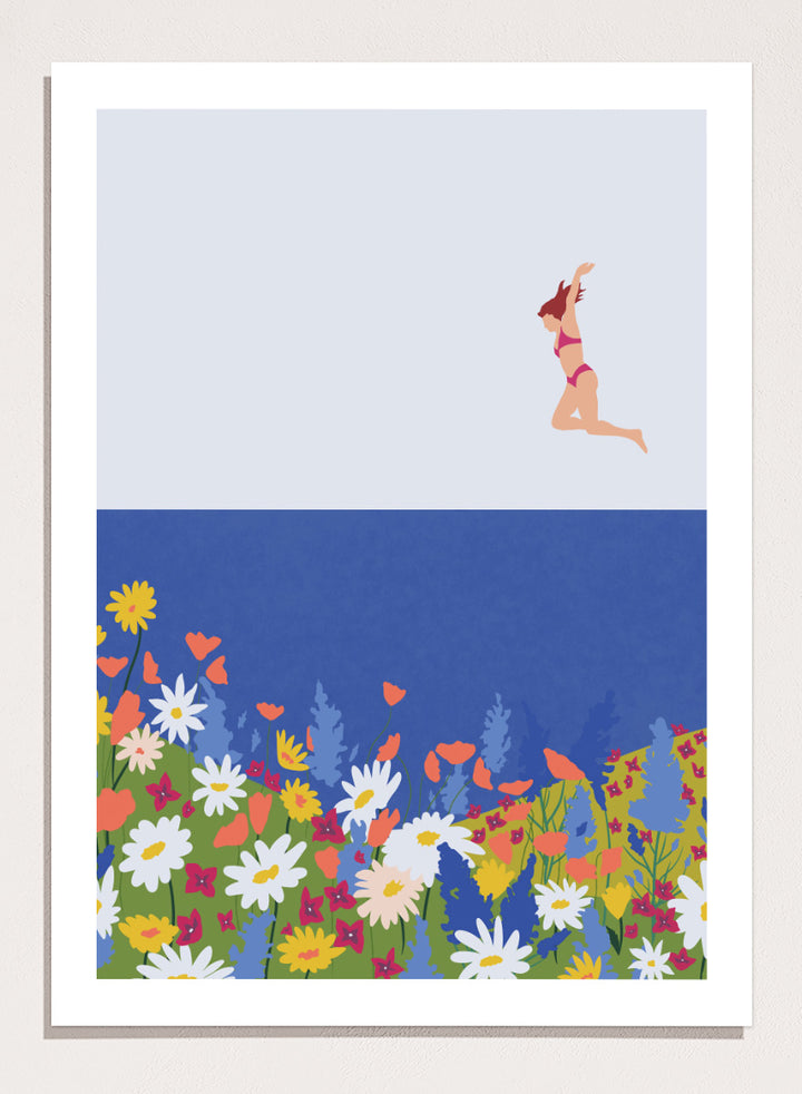 A framed art print featuring a minimalist illustration of a woman in a pink bikini jumping into a blue sea with a colorful wildflower meadow below. Wildflower Summer Jump art print by Ceyda Alasar features a joyful figure above colorful blooms, bringing playful summer energy to your walls.