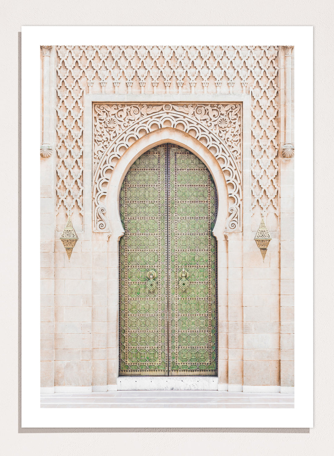 Decorative archway with ornate green door on a light stone wall. Ornate Moroccan Green Door by Henrike Schenk is a Moroccan architecture print featuring an ornate green door, Islamic patterns, and historic stone details.