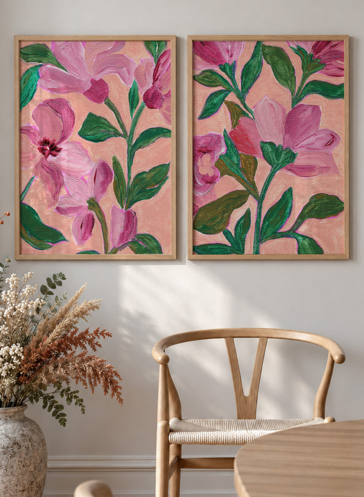 Two framed floral art prints with pink flowers and green leaves on a peach background. Shop Vibrant Pink Botanicals by Nikita Jariwala, a set of 2 floral wall art prints posters featuring oversized pink flowers and lush botanical artwork.