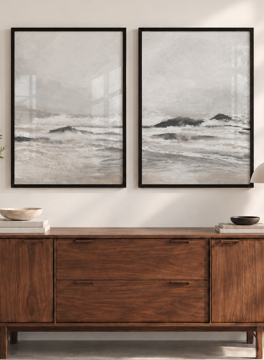 Shop September Coast by Dan Hobday, a set of 2 coastal wall art prints posters featuring rolling waves, dark rocks, misty skies, and soft neutral tones.