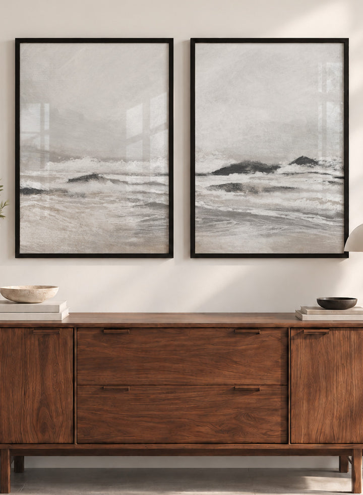 Shop September Coast by Dan Hobday, a set of 2 coastal wall art prints posters featuring rolling waves, dark rocks, misty skies, and soft neutral tones.
