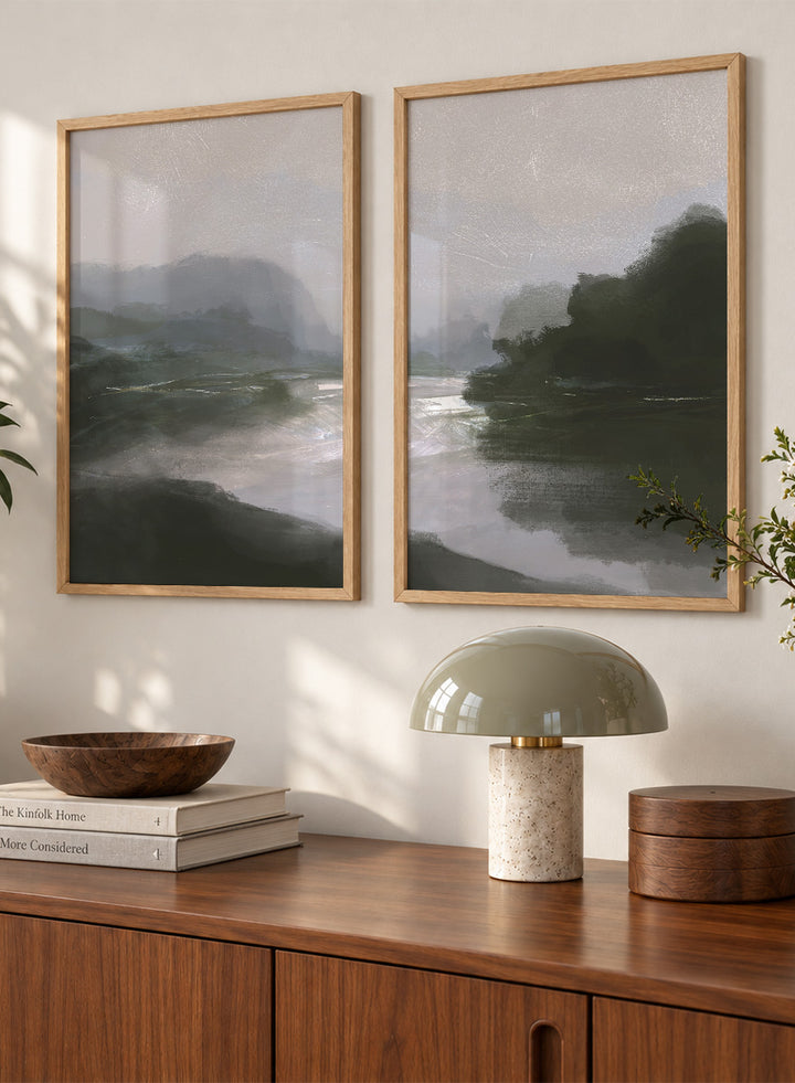 Shop Tranquillitas by Dan Hobday, a set of 2 landscape wall art prints posters featuring misty water, tree-lined banks, distant hills, and deep grey green tones.