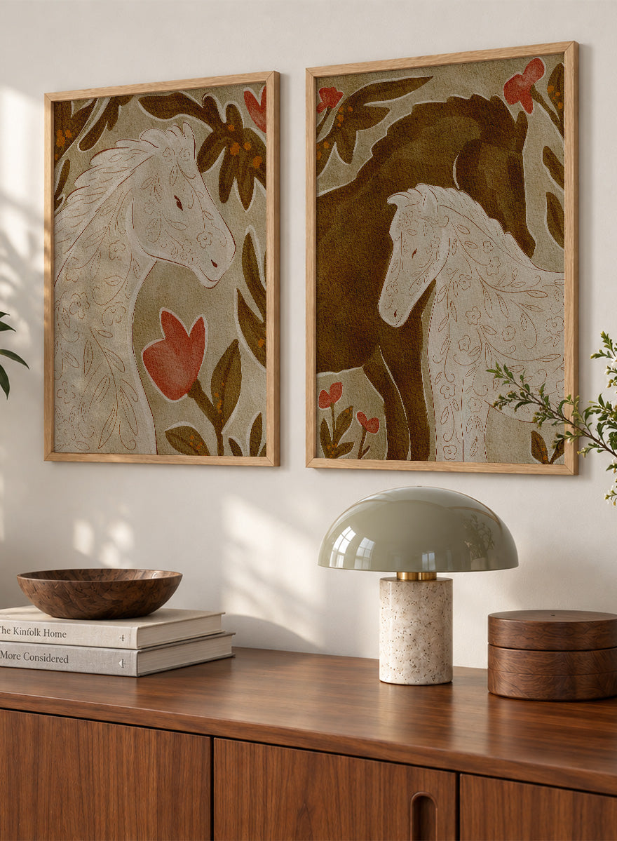 Two framed art prints depicting stylized horses in warm earthy tones. Shop Wildflower Horses by Nikita Jariwala, a set of 2 horse wall art prints posters featuring floral horse portraits, botanical details, and warm brown tones.