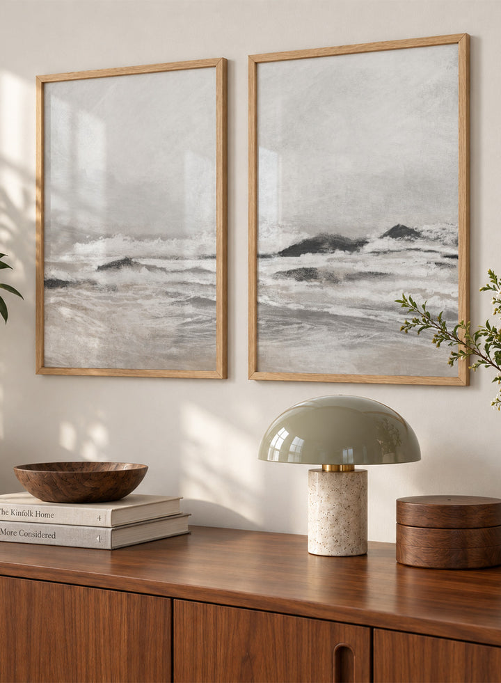 Shop September Coast by Dan Hobday, a set of 2 coastal wall art prints posters featuring rolling waves, dark rocks, misty skies, and soft neutral tones.